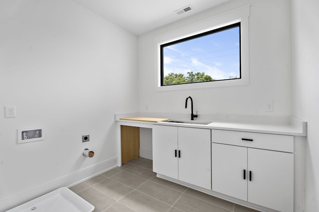 washroom with cabinets, hookup for a washing machine, electric dryer hookup, sink, and light tile patterned floors