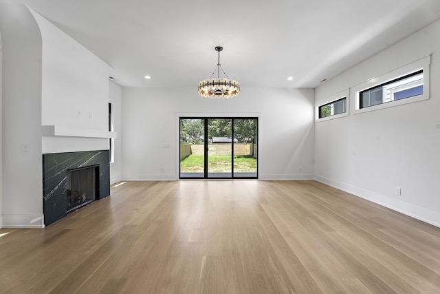 unfurnished living room featuring a fireplace, light hardwood / wood-style flooring, and a chandelier