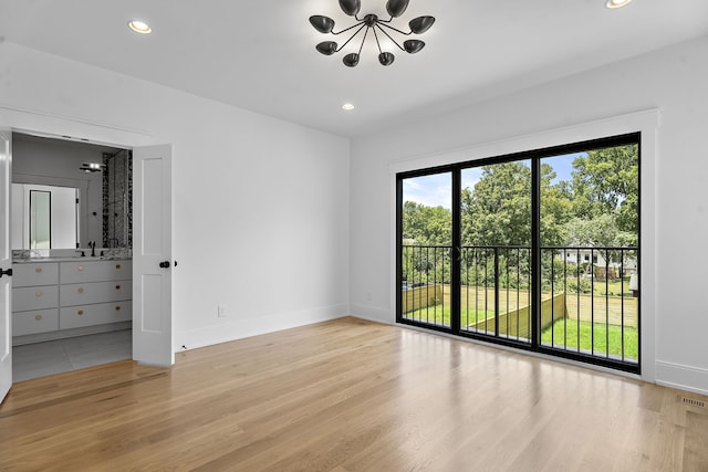 unfurnished room with a notable chandelier and light wood-type flooring