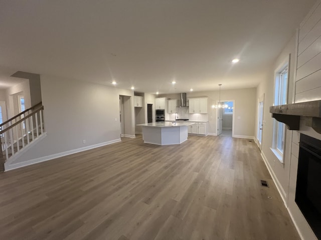 unfurnished living room with sink, hardwood / wood-style floors, and a notable chandelier