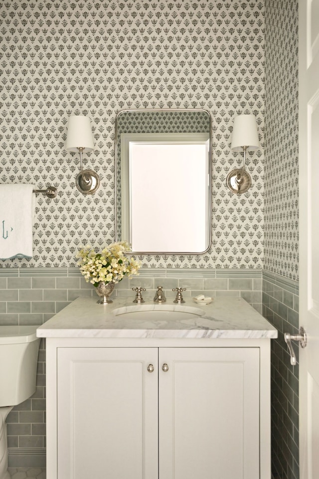 bathroom featuring vanity, toilet, and tile walls