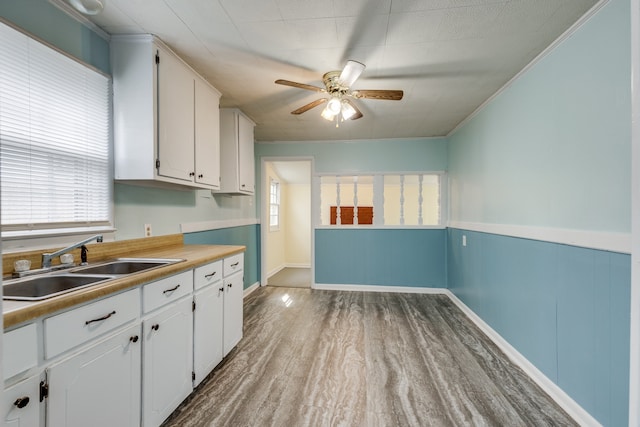 kitchen featuring white cabinets, sink, light hardwood / wood-style flooring, ceiling fan, and ornamental molding