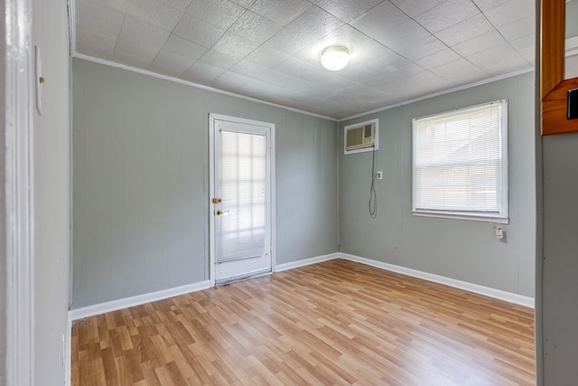 empty room with light hardwood / wood-style flooring, a wall mounted air conditioner, and ornamental molding