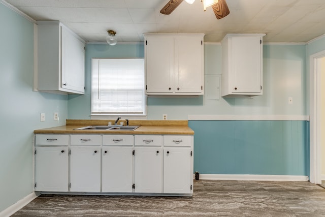 kitchen with white cabinetry, ornamental molding, and sink