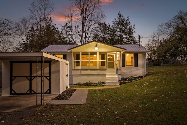 outdoor structure at dusk with a lawn and a sunroom