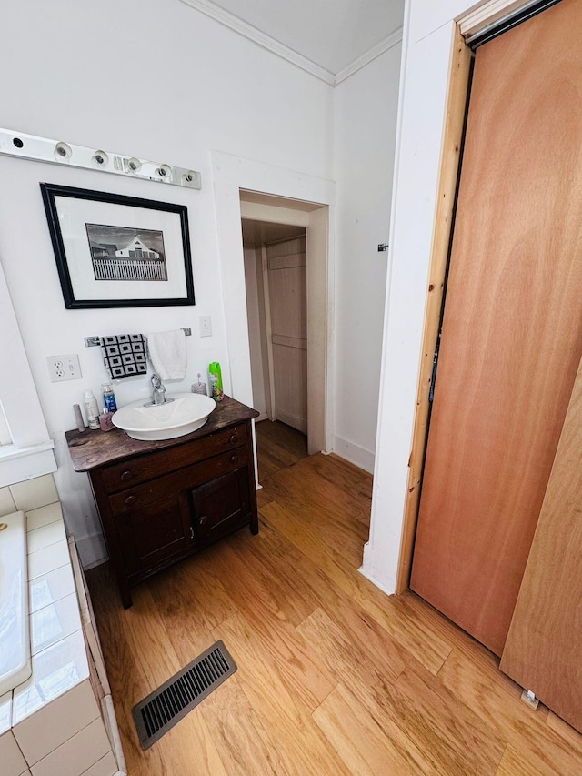 bathroom with hardwood / wood-style floors, vanity, and ornamental molding