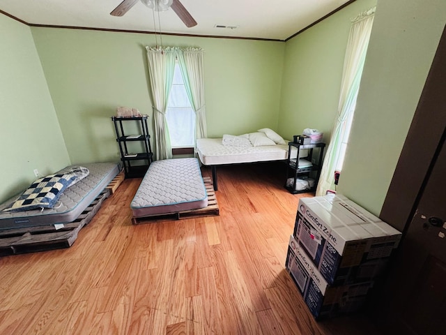 bedroom with light hardwood / wood-style floors, ceiling fan, and crown molding