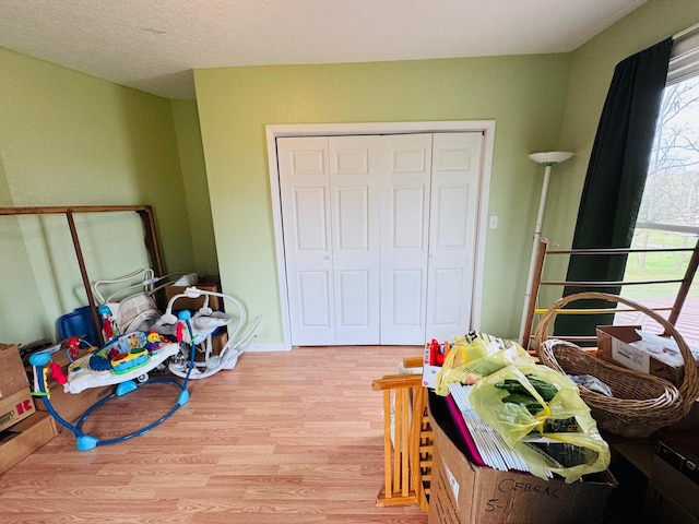 recreation room featuring a textured ceiling and light hardwood / wood-style flooring