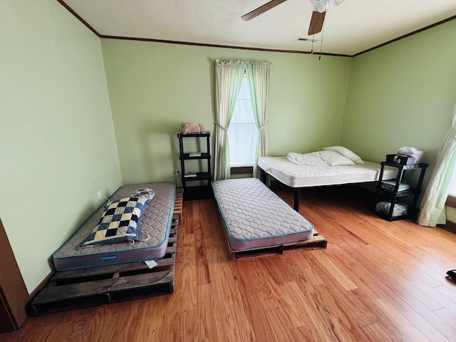 bedroom featuring ceiling fan, crown molding, and wood-type flooring