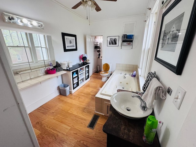 bathroom with vanity, a bath, hardwood / wood-style flooring, toilet, and ornamental molding