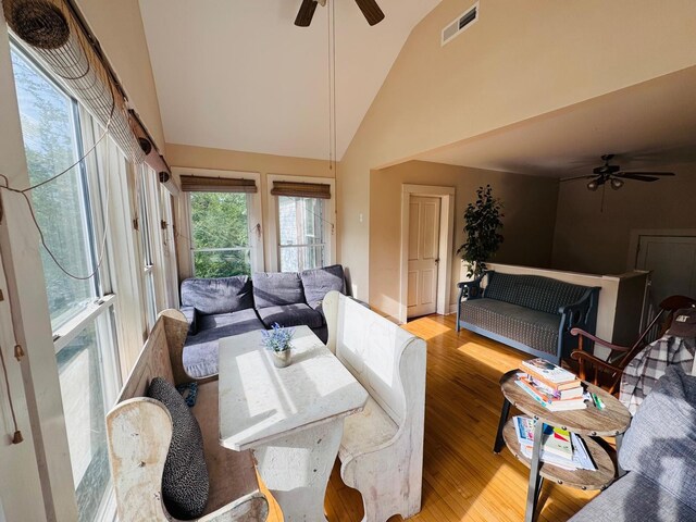 living room with ceiling fan, high vaulted ceiling, and light hardwood / wood-style flooring