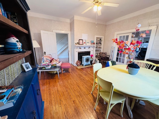 dining space featuring wood-type flooring, ceiling fan, and crown molding