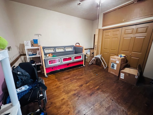 bedroom with ceiling fan, dark wood-type flooring, and a closet