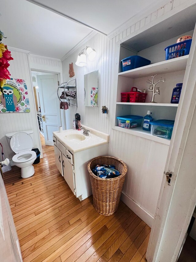 bathroom with vanity, crown molding, hardwood / wood-style flooring, toilet, and wood walls