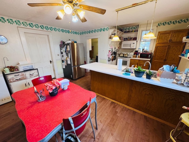 kitchen with white appliances, hanging light fixtures, dark wood-type flooring, and ceiling fan