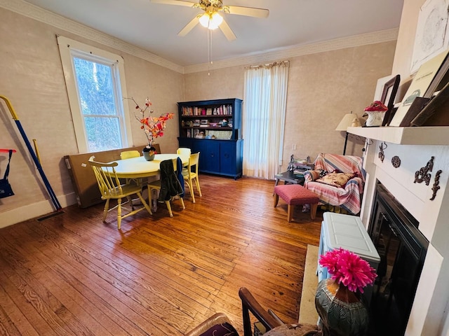 dining space featuring hardwood / wood-style flooring, ceiling fan, ornamental molding, and a tile fireplace