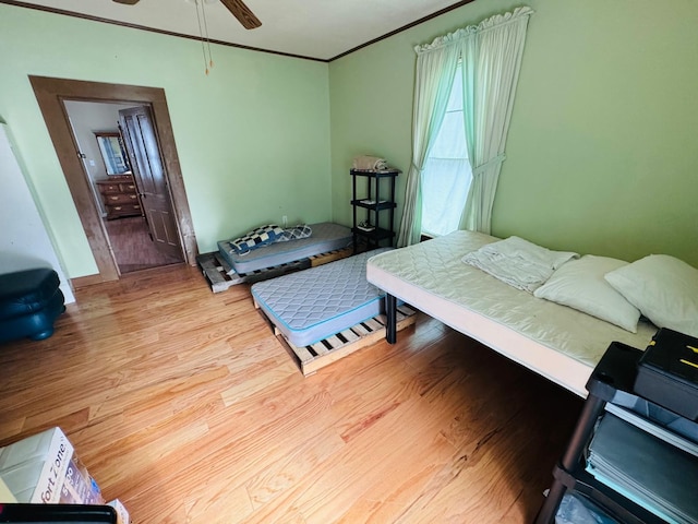 bedroom featuring ceiling fan, light wood-type flooring, and crown molding