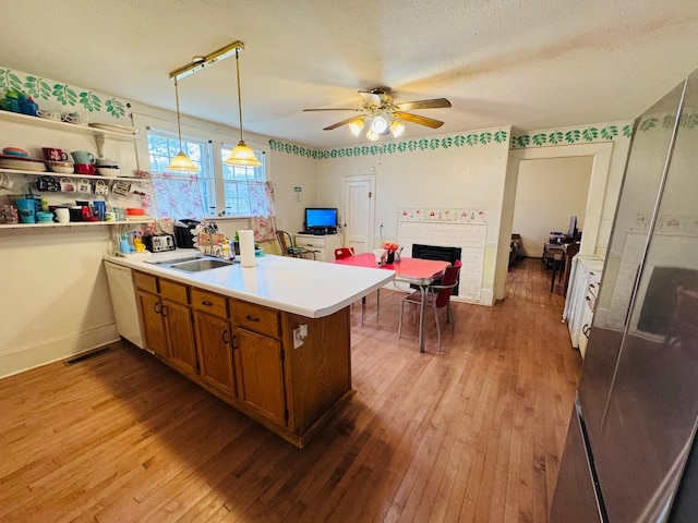 kitchen featuring a brick fireplace, decorative light fixtures, kitchen peninsula, and light hardwood / wood-style flooring