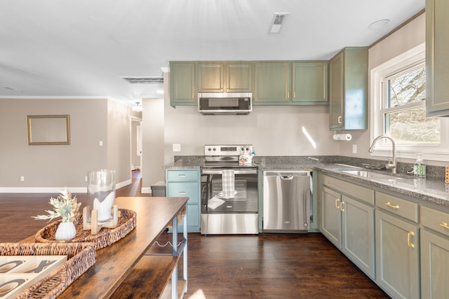 kitchen featuring dark stone counters, stainless steel appliances, dark wood-type flooring, sink, and green cabinetry