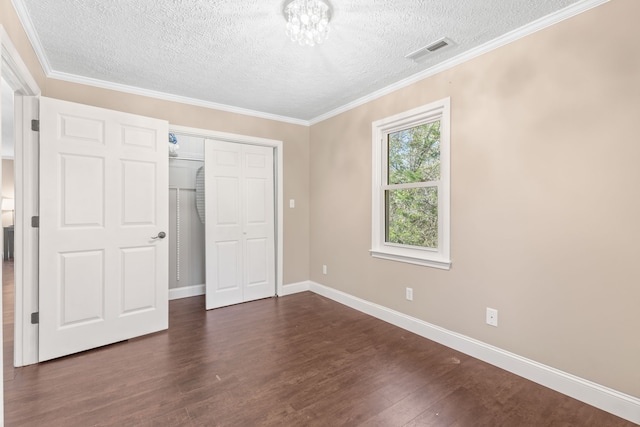 unfurnished bedroom featuring a textured ceiling, dark hardwood / wood-style floors, crown molding, and a closet