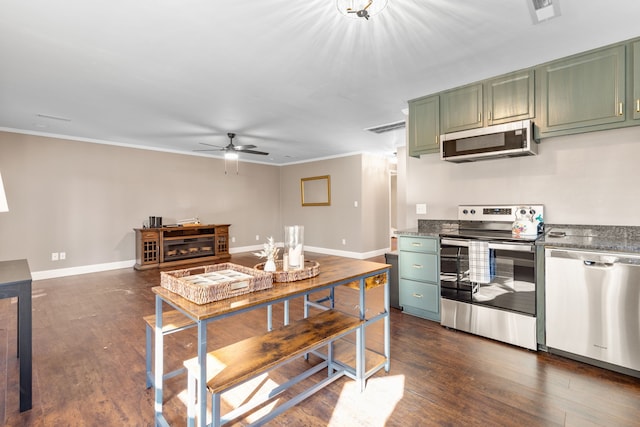 kitchen with green cabinets, ceiling fan, ornamental molding, appliances with stainless steel finishes, and dark hardwood / wood-style flooring