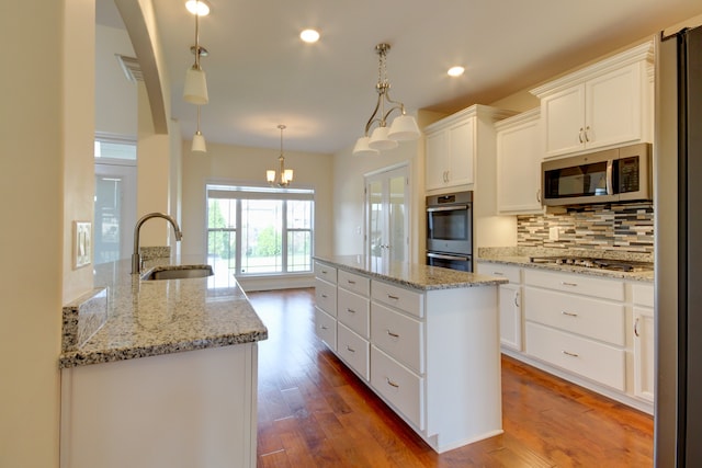 kitchen featuring sink, stainless steel appliances, hardwood / wood-style floors, pendant lighting, and white cabinets