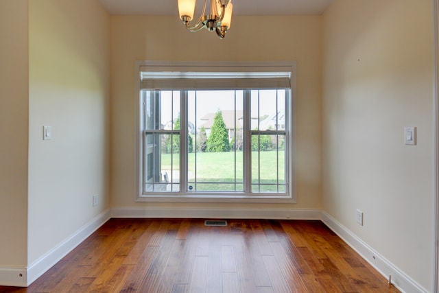 empty room featuring dark hardwood / wood-style floors and an inviting chandelier