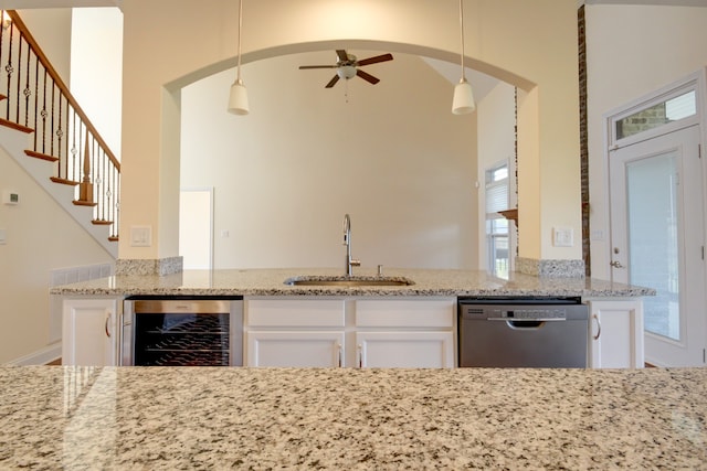 kitchen with stainless steel dishwasher, beverage cooler, sink, decorative light fixtures, and white cabinetry