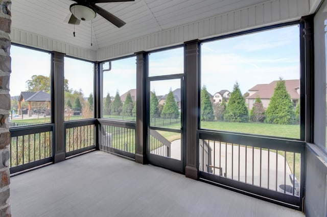 unfurnished sunroom featuring lofted ceiling, ceiling fan, and a healthy amount of sunlight