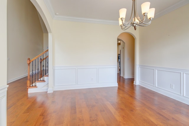 unfurnished room featuring hardwood / wood-style floors, a notable chandelier, and ornamental molding