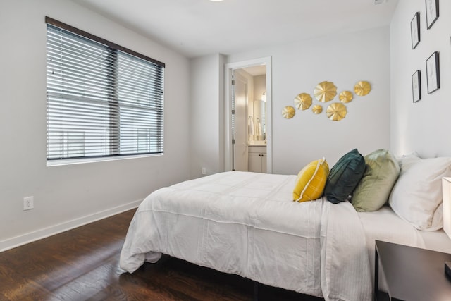 bedroom featuring ensuite bathroom and dark wood-type flooring