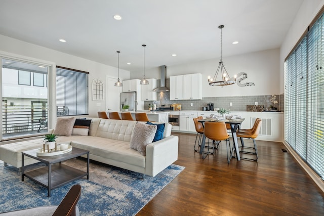 living room featuring plenty of natural light, dark wood-type flooring, and a notable chandelier