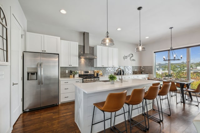 kitchen featuring decorative light fixtures, wall chimney exhaust hood, stainless steel appliances, and dark hardwood / wood-style floors