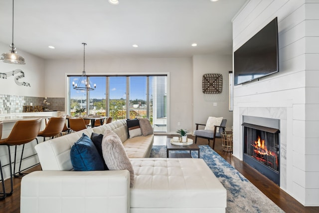 living room with dark wood-type flooring, a tile fireplace, and a chandelier