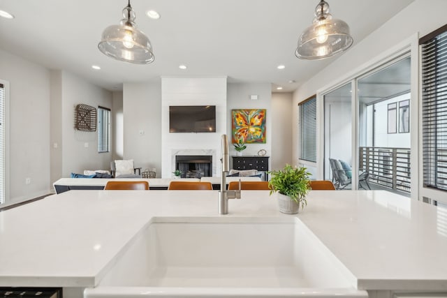 kitchen with a center island with sink, sink, a premium fireplace, and hanging light fixtures