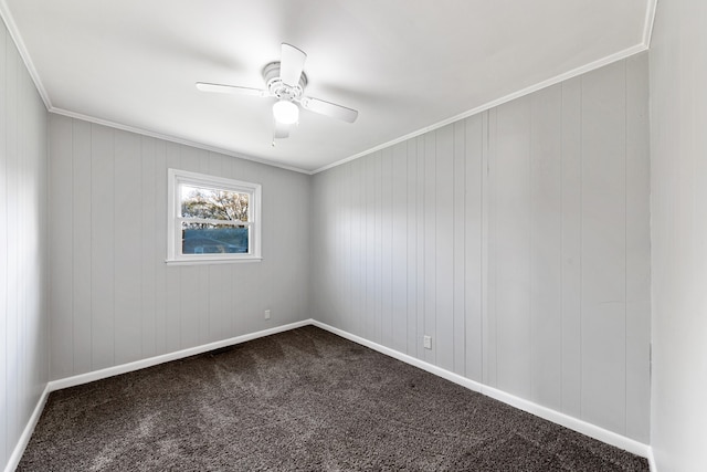 carpeted spare room with ceiling fan, crown molding, and wood walls