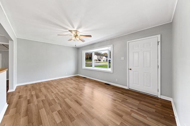 unfurnished living room featuring ceiling fan, ornamental molding, and light wood-type flooring