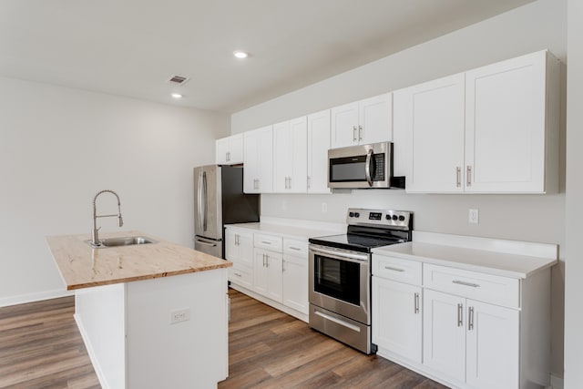 kitchen with white cabinetry, sink, dark hardwood / wood-style flooring, an island with sink, and appliances with stainless steel finishes