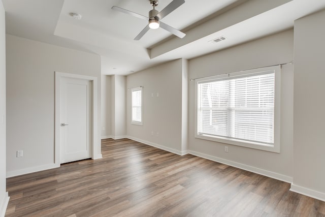 spare room featuring wood-type flooring, a tray ceiling, and ceiling fan