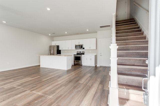 kitchen with a kitchen island, white cabinetry, appliances with stainless steel finishes, and light hardwood / wood-style flooring