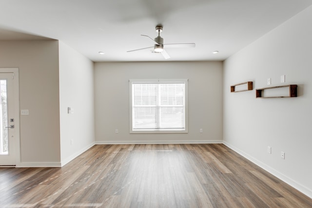 empty room with a wealth of natural light, ceiling fan, and wood-type flooring