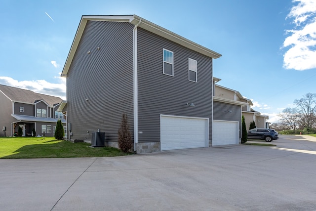 view of home's exterior with a garage, cooling unit, and a lawn