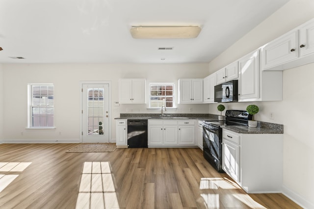 kitchen with white cabinets, sink, light hardwood / wood-style floors, and black appliances