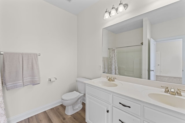 bathroom with toilet, hardwood / wood-style floors, vanity, and walk in shower