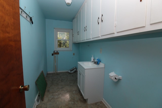 clothes washing area featuring cabinets and sink