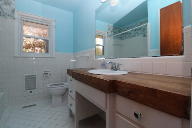 full bathroom featuring tile patterned floors, vanity, heating unit, tile walls, and toilet