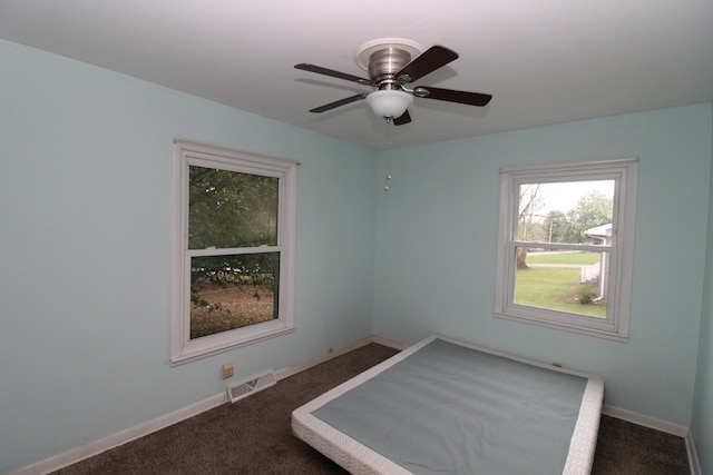 unfurnished bedroom featuring dark colored carpet and ceiling fan