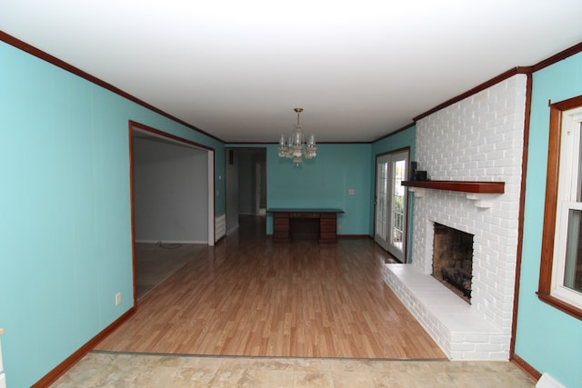 unfurnished living room with hardwood / wood-style floors, ornamental molding, a fireplace, and an inviting chandelier