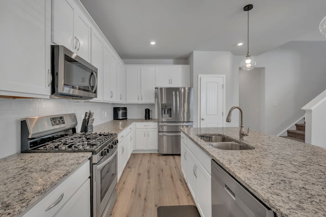 kitchen featuring light stone countertops, stainless steel appliances, sink, light hardwood / wood-style floors, and white cabinetry