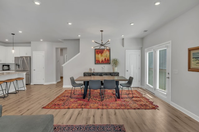 dining space featuring light hardwood / wood-style flooring and an inviting chandelier